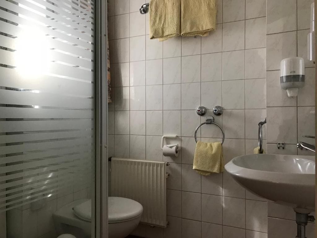 A bathroom with a toilet, a sink, a towel rack, and a shower area.