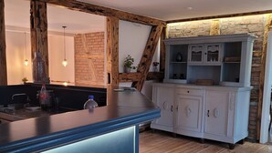 Een keuken met een houten vloer, een blauw aanrecht en een wit kastje met glazen deuren.