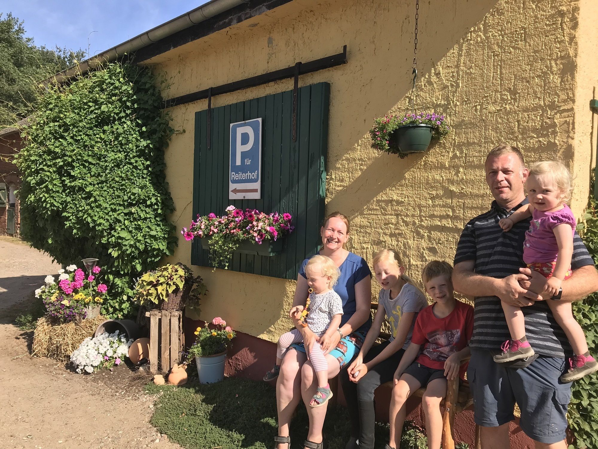 A family sitting outside a building with a 'P' sign indicating parking.