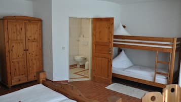 A small, compact room with a bunk bed, wooden wardrobe, and a bathroom visible through an open door.