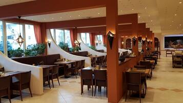 A restaurant with a curved seating arrangement, multiple tables, and chairs.