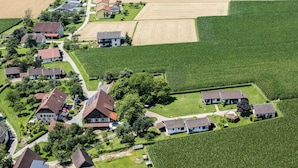 An aerial view of a residential area with houses, green fields, and a clear sky. - Erlebnisbauernhof Tschom (Sankt Kanzian am Klopeiner See)
