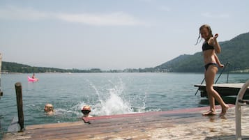 Un muelle de madera que se adentra en un lago, con una persona al final.