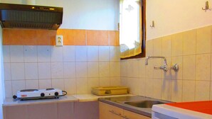 A compact kitchen with a stove, sink, and a small refrigerator. - Pandora Studios (South Pelion)