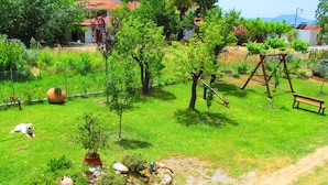 A garden with a swing set, a dog on a leash, and a dirt path. - Pandora Studios (South Pelion)