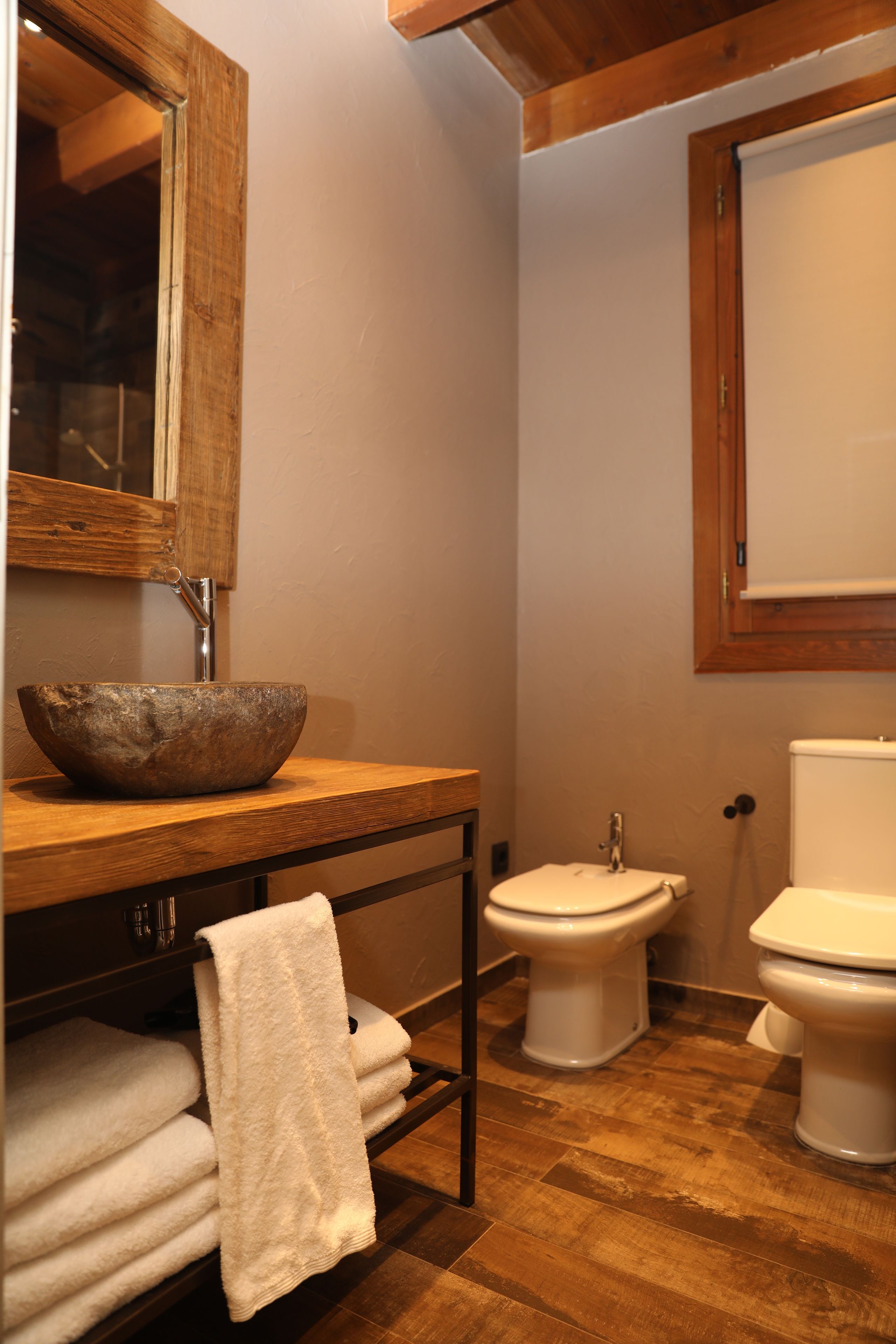 Un bagno con un mobile bagno in legno, un lavabo capiente, un bidet e un water.