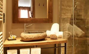 A bathroom with a stone sink, a mirror, and a shower. - Hotel Puig Francó (Camprodon)