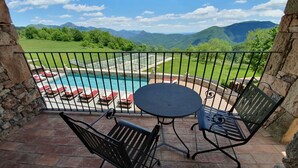 Un balcon avec une piscine, des chaises longues et une table.
