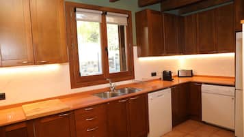 Cucina con mobili in legno, lavello, lavastoviglie e finestra con persiane.