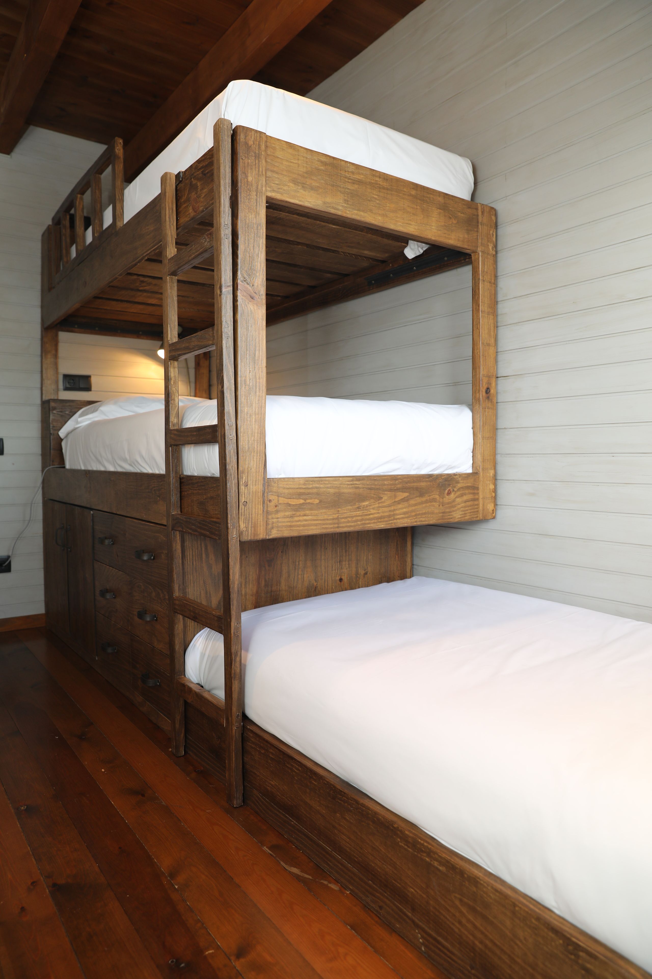 Una cama litera con estructura de madera y ropa de cama blanca.