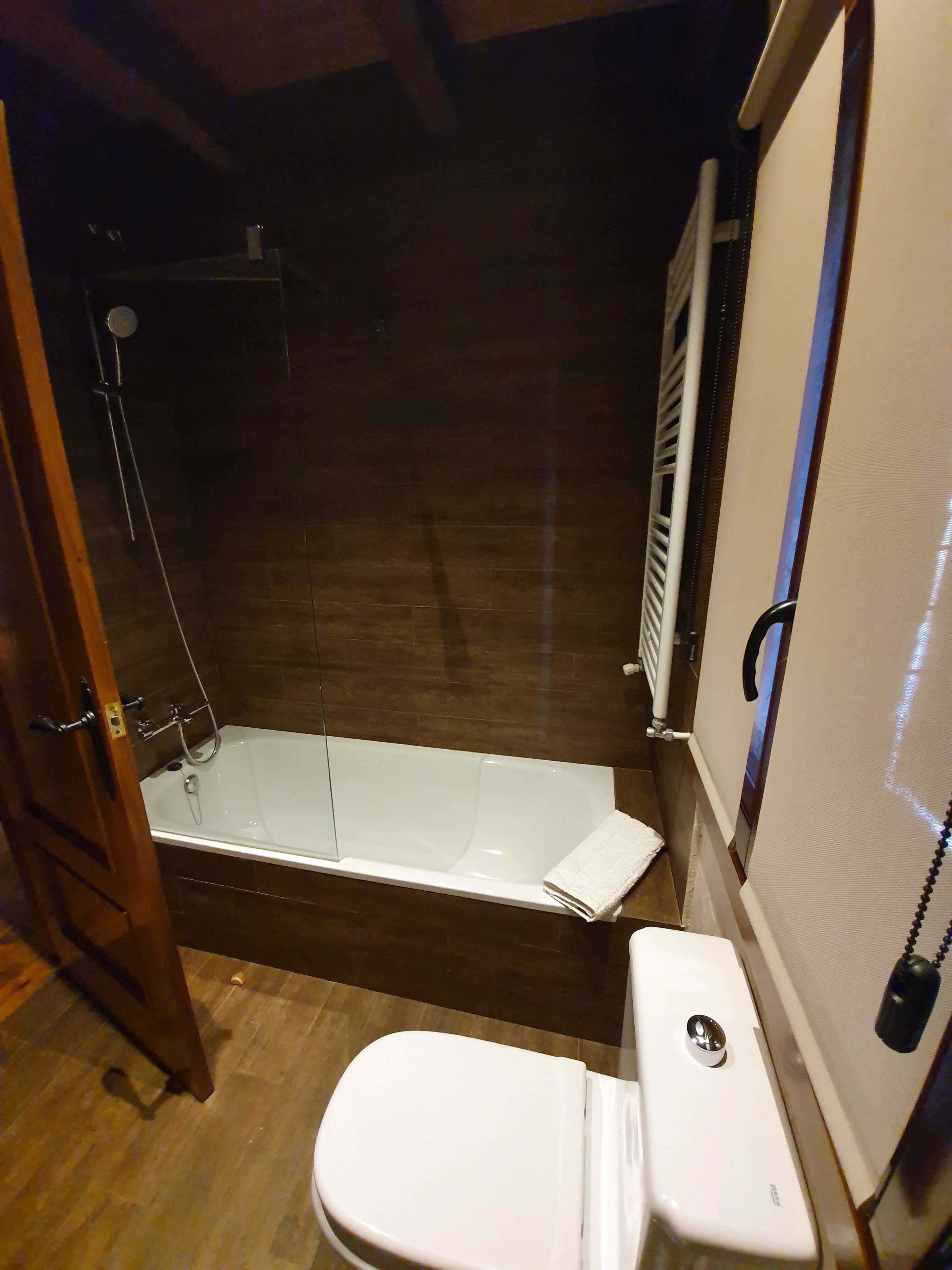 Un baño con bañera, inodoro y suelo de madera.