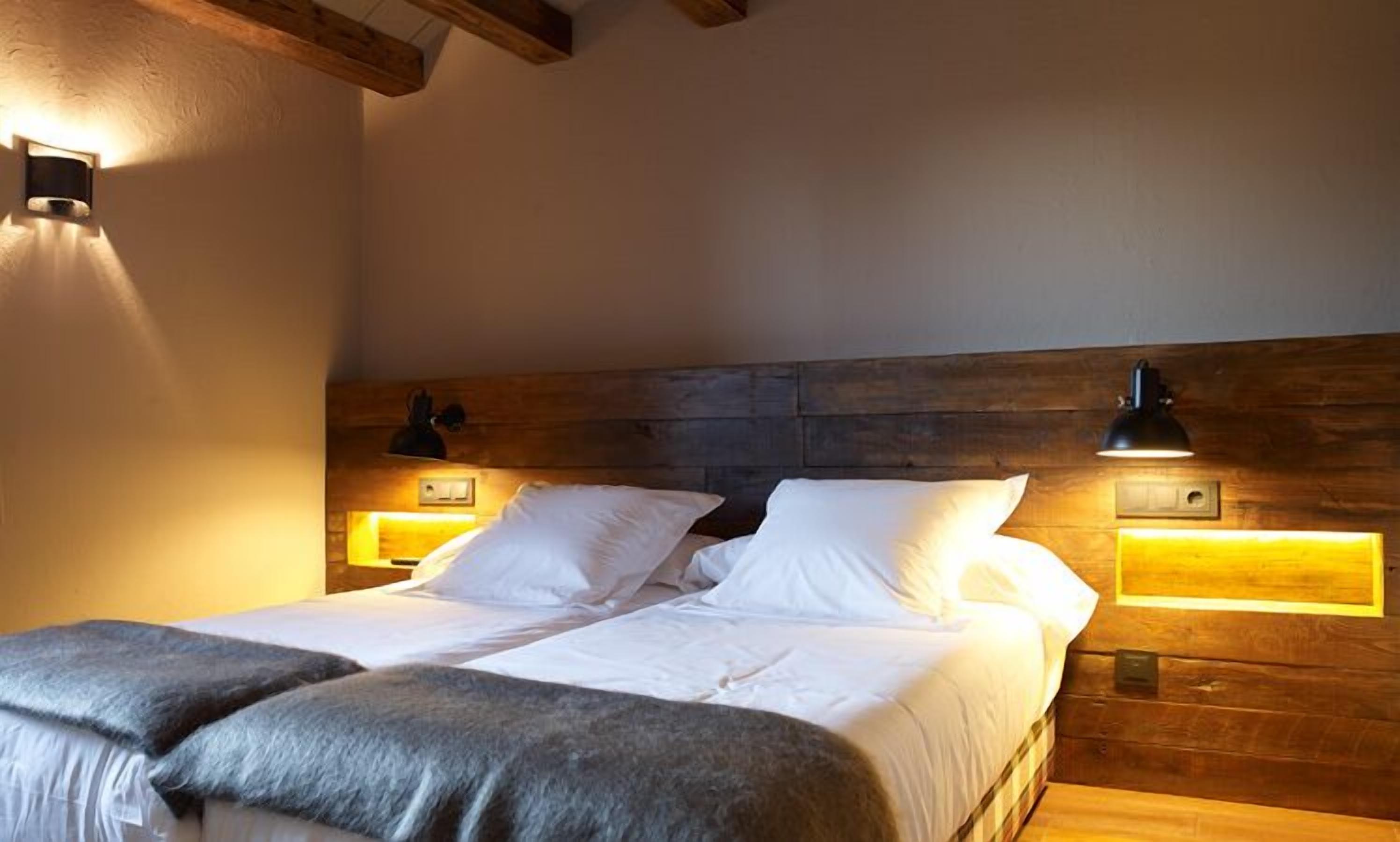 Ein Schlafzimmer mit einem hölzernen Kopfteil, zwei Nachttischlampen und einem Bett mit weißer Bettwäsche.