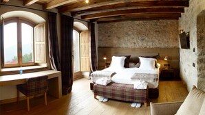 Une chambre avec un plafond en bois, un lit avec des oreillers, un bureau avec une chaise et une fenêtre avec des rideaux.