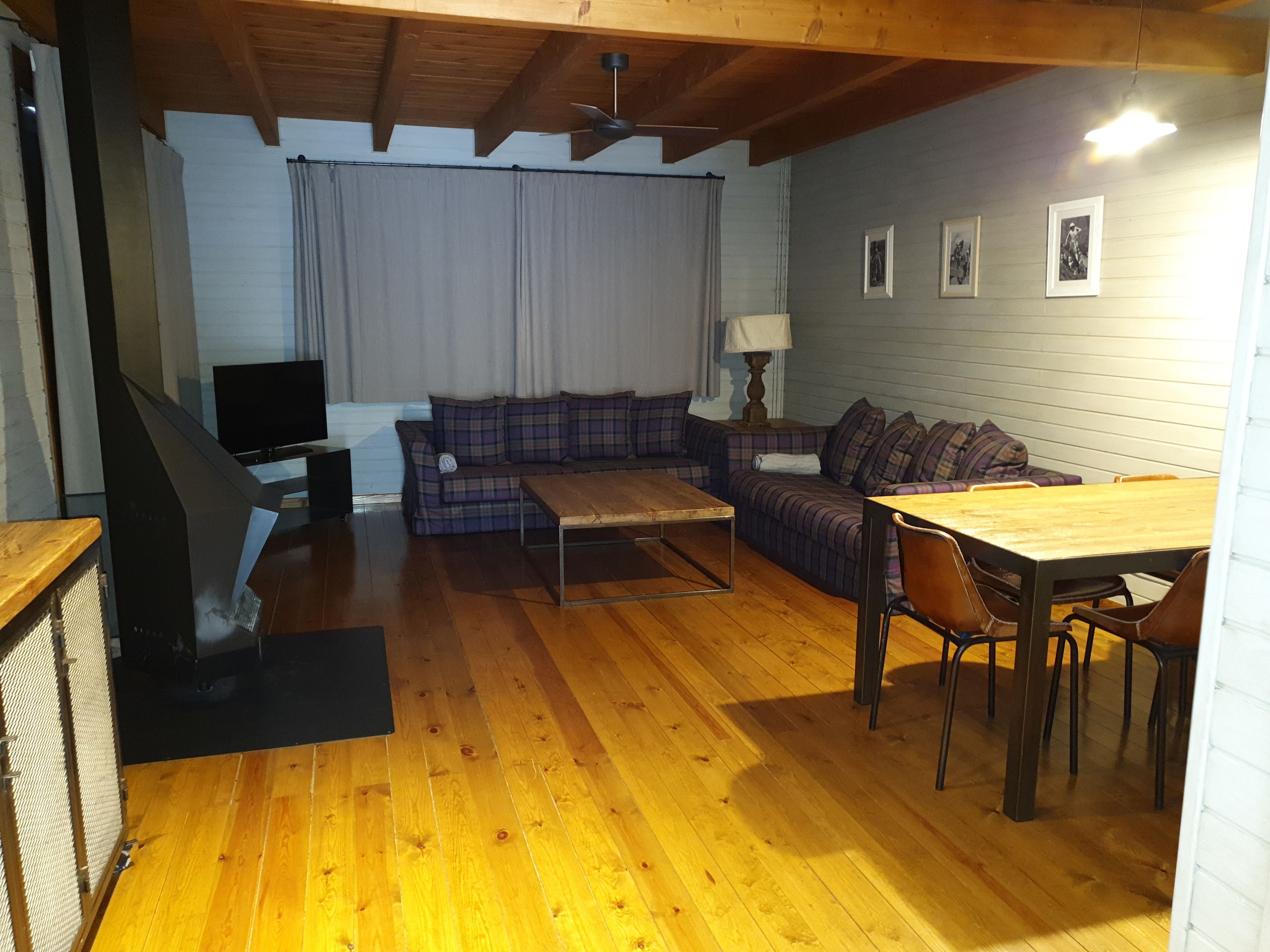 Ein gemütliches Wohnzimmer mit Holzboden, einer Couch, einem Couchtisch und einem Esstisch mit Stühlen.