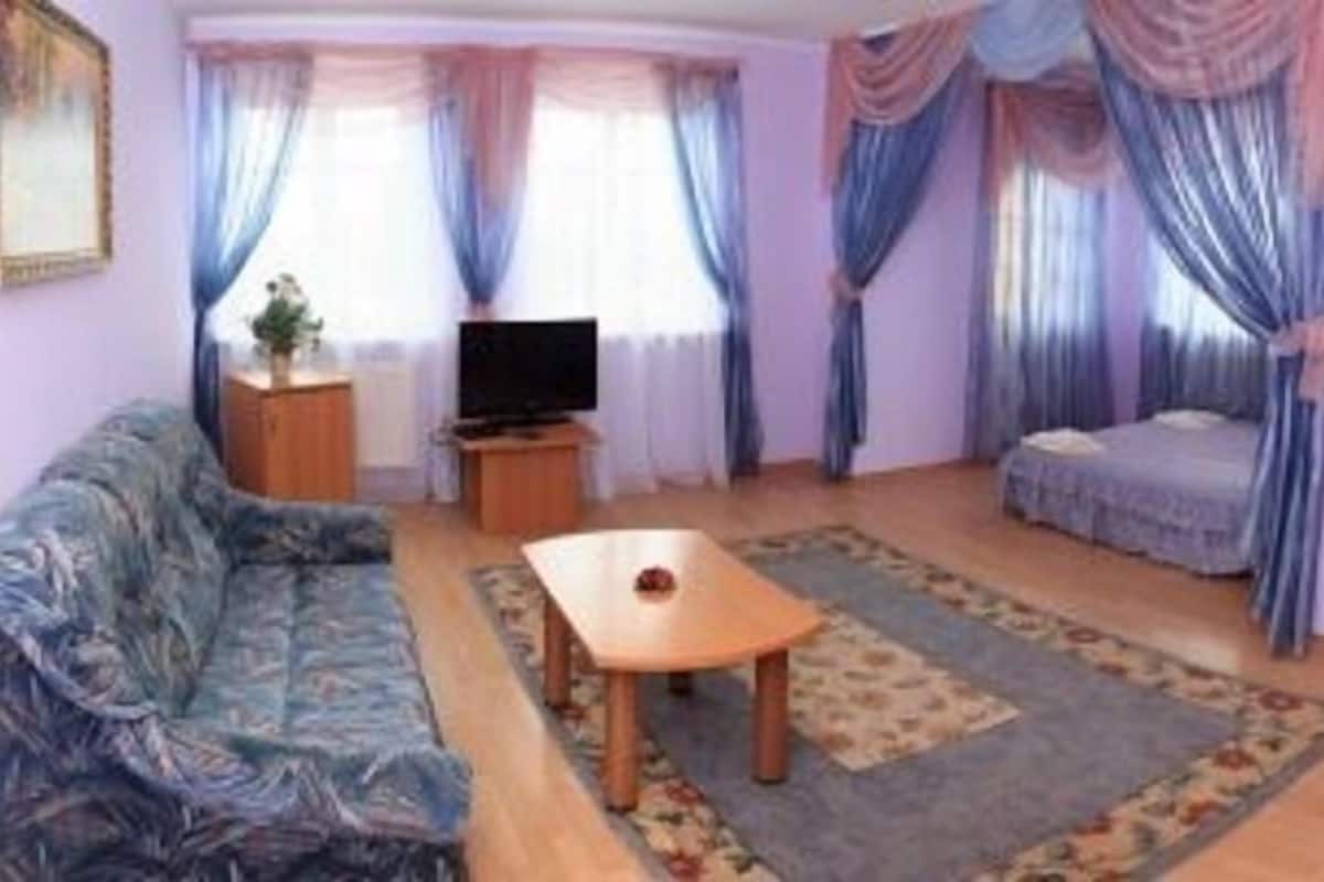 Una sala de estar con sofá, televisión, mesa de centro y cama.