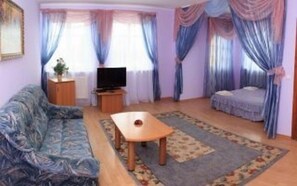 A living room with a sofa, a TV, a coffee table, and a bed. - Kaufman (Konopnytsia)