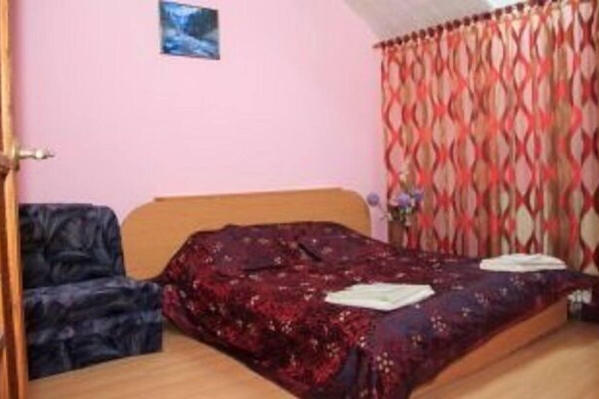 Un dormitorio con cama, una silla, una mesita y una ventana con cortinas.