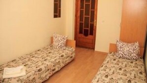 A small, single-room accommodation with two single beds, a wooden door, and a small window. - Kaufman (Konopnytsia)