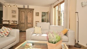 A living room with a sofa, a coffee table with a plant, a wooden cabinet, and a floor lamp. - Villa in Crillon-le-Brave near Mont Ventoux (Crillon-le-Brave)