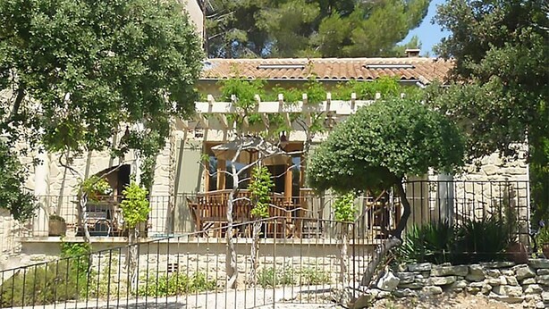 A stone building with a tiled roof, surrounded by trees and a fenced garden area. - Villa in Crillon-le-Brave near Mont Ventoux (Crillon-le-Brave)