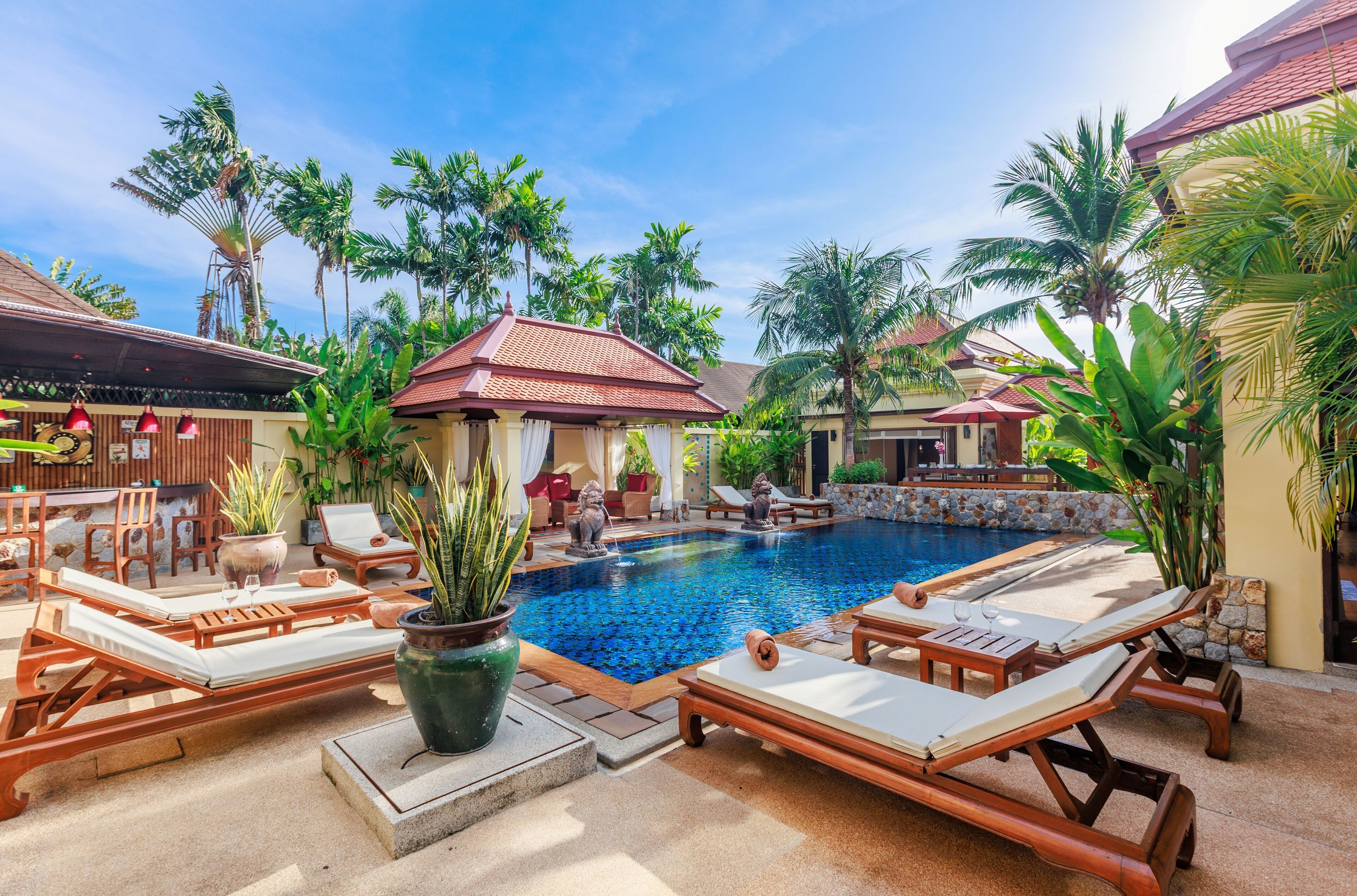 A poolside area with lounge chairs, a pool, and tropical plants.