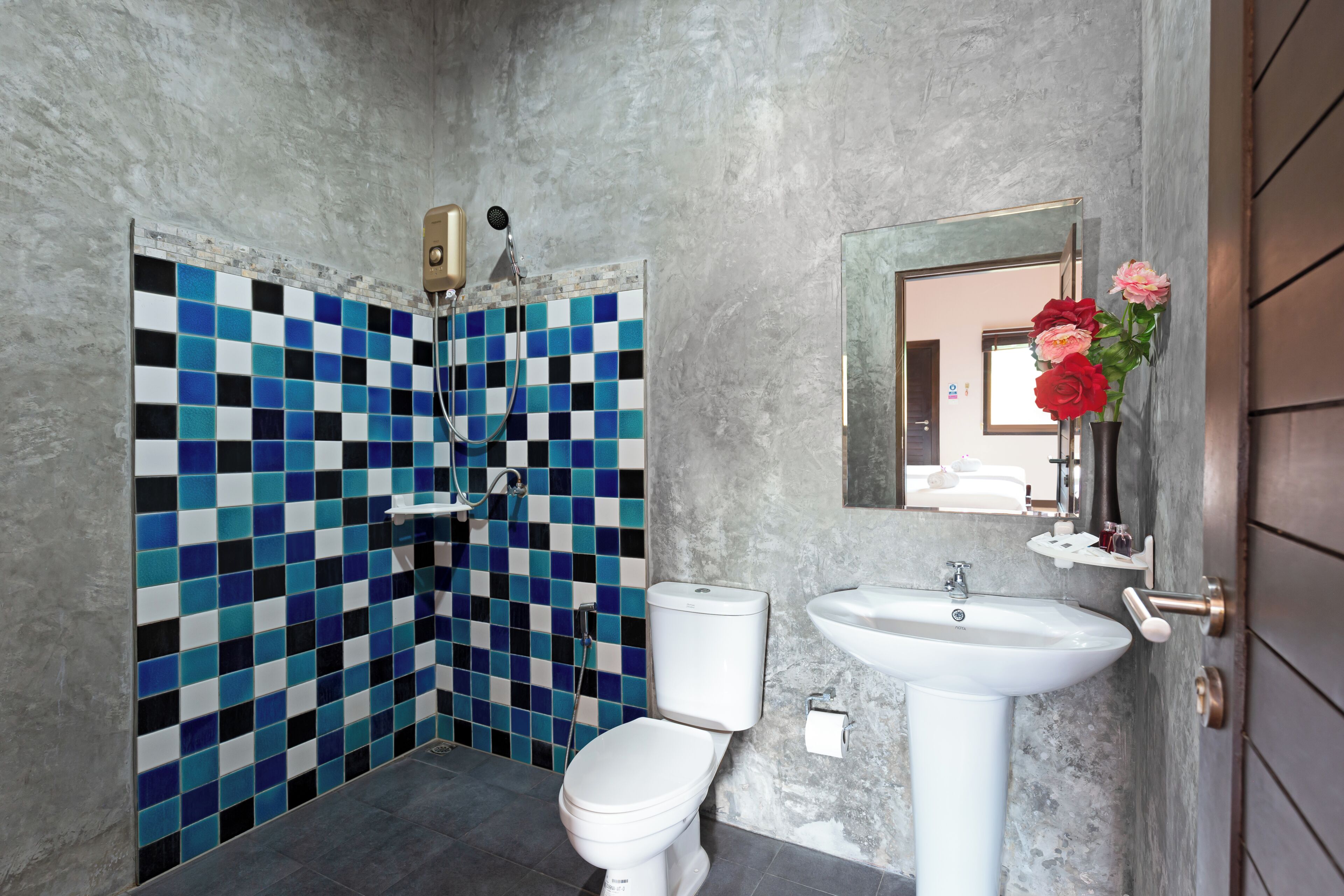Ein Badezimmer mit Wandfliesen im Schachbrettmuster, Toilette, Waschbecken und Dusche.