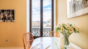 Un comedor con una mesa, sillas, un florero con flores y un cuadro en la pared.