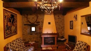 Una sala de estar acogedora con chimenea, muebles de madera y un candelabro.