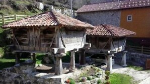 Dos construcciones de madera con techos de tejas, posiblemente casas para pájaros, sobre una base de piedra con macetas.