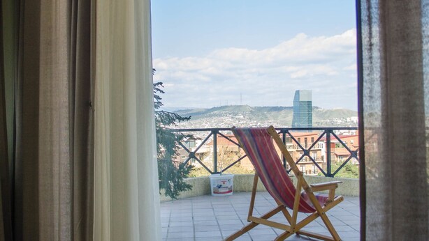 Une chambre avec vue sur un balcon, un hamac et le paysage urbain.