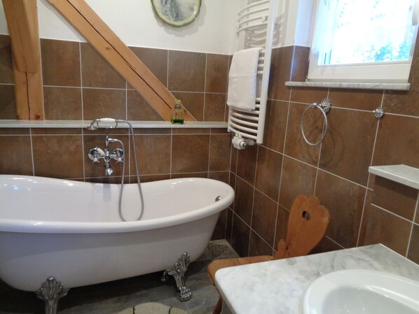 A bathroom with a freestanding bathtub, a sink, and a window. - Manor at the moated castle (Döbschütz)