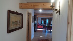 A hallway with wooden beams, a red sofa, a dining table, and a chandelier. - Manor at the moated castle (Döbschütz)