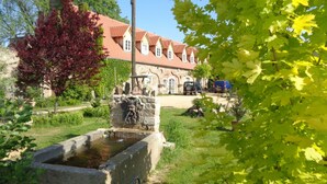 A stone fountain in a garden with a building in the background. - Manor at the moated castle (Döbschütz)