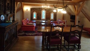 A cozy loft-style room with exposed wooden beams, a stone wall, and a red leather sofa. - Manor at the moated castle (Döbschütz)
