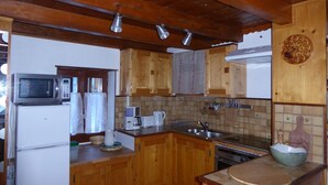 A kitchen with wooden cabinets, a microwave, a refrigerator, a sink, and a stove.