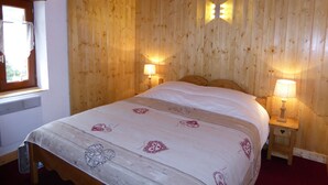 A wooden-paneled bedroom with a bed, two bedside lamps, and a window with curtains.