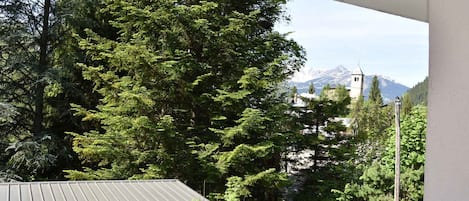 Un balcón con vistas a un bosque y una montaña al fondo.