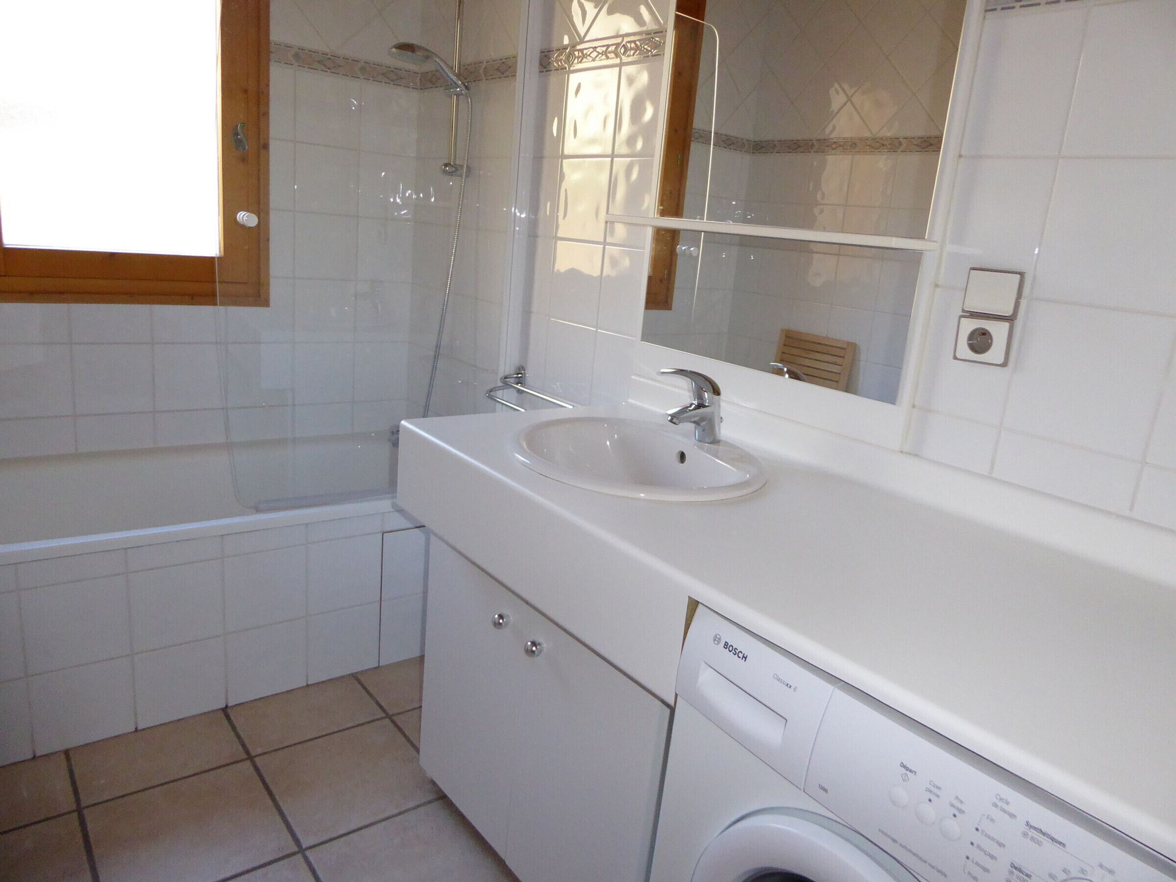 A bathroom with a sink, mirror, and washing machine.