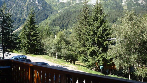Vista de la montaña con una terraza de madera que domina una carretera y un coche estacionado.