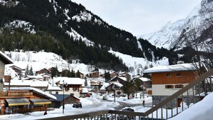 Un pueblo en la montaña cubierto de nieve con edificios de madera, un telesilla y un restaurante llamado "Galerie de la Vanoise".