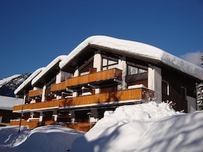 Ein mehrstöckiges Holzgebäude mit Balkonen, umgeben von Schnee und Bergen.