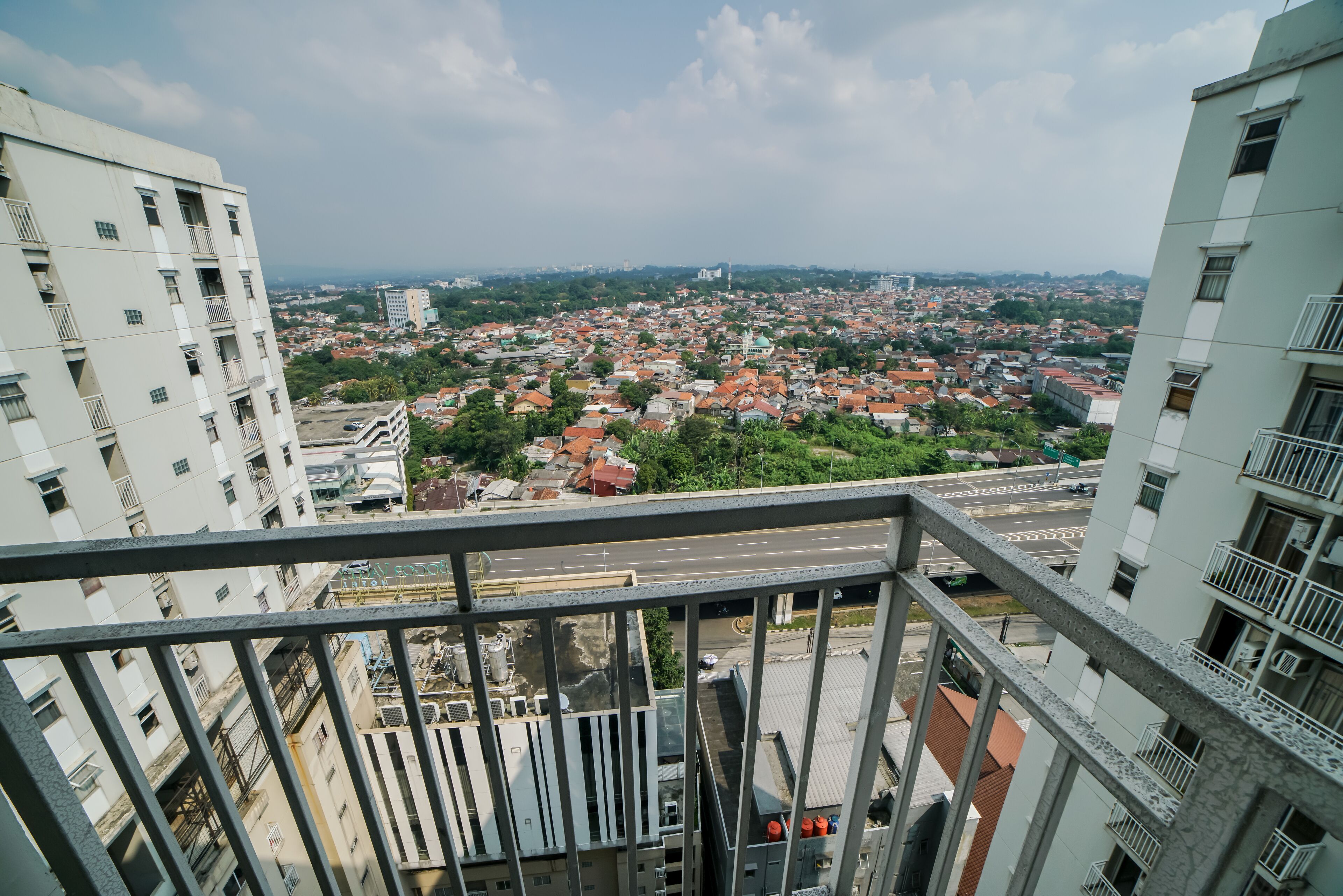 Un edificio alto con varios balcones que dan a una zona urbana densamente poblada, con diversos edificios y calles.