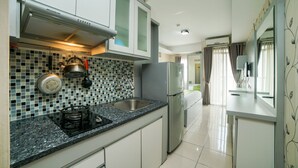 A modern kitchen with a gas stove, stainless steel appliances, and a tiled backsplash. - Apartment Bogor Valley (Bogor)
