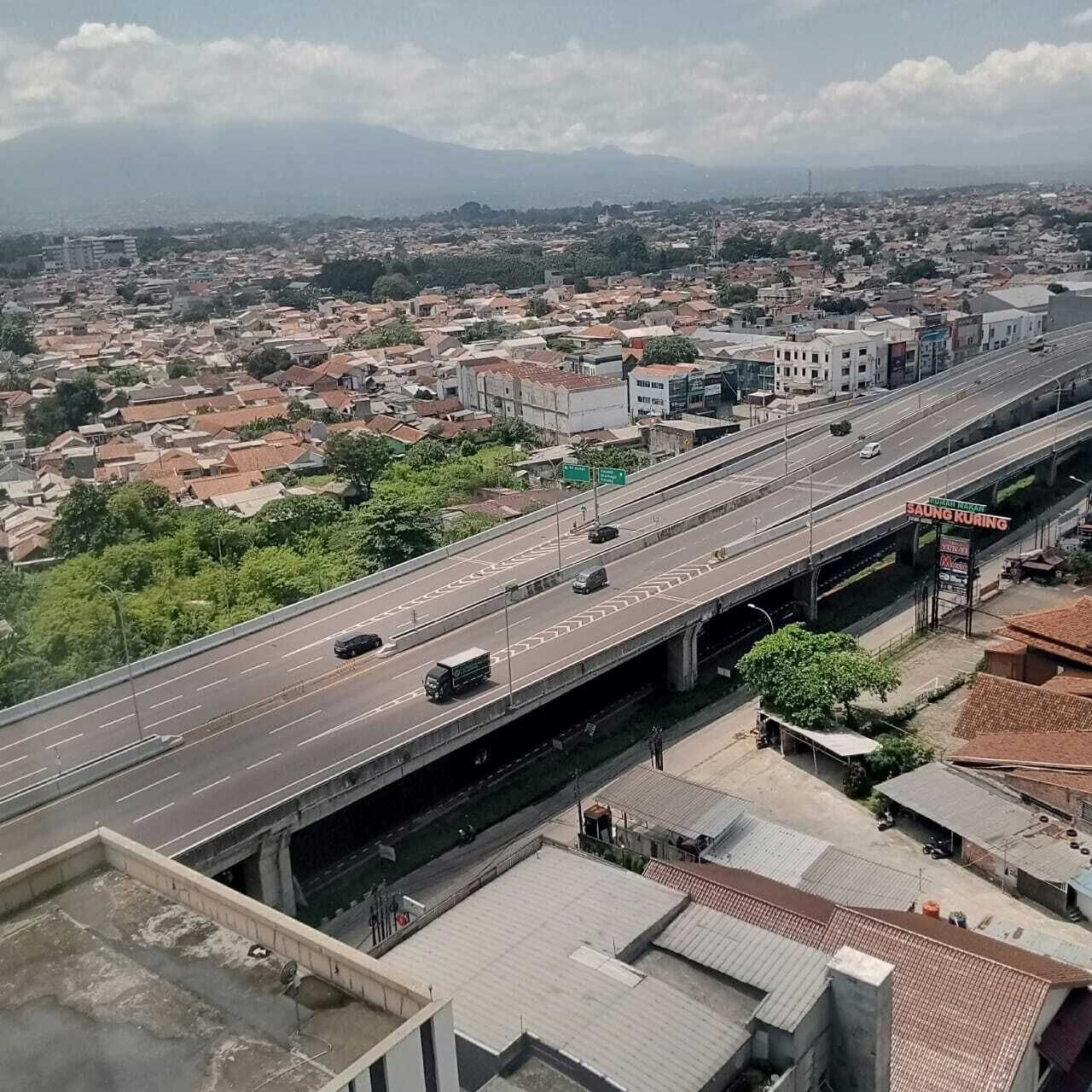 Une autoroute à plusieurs niveaux, avec des véhicules, des ponts et une vue lointaine sur la ville.
