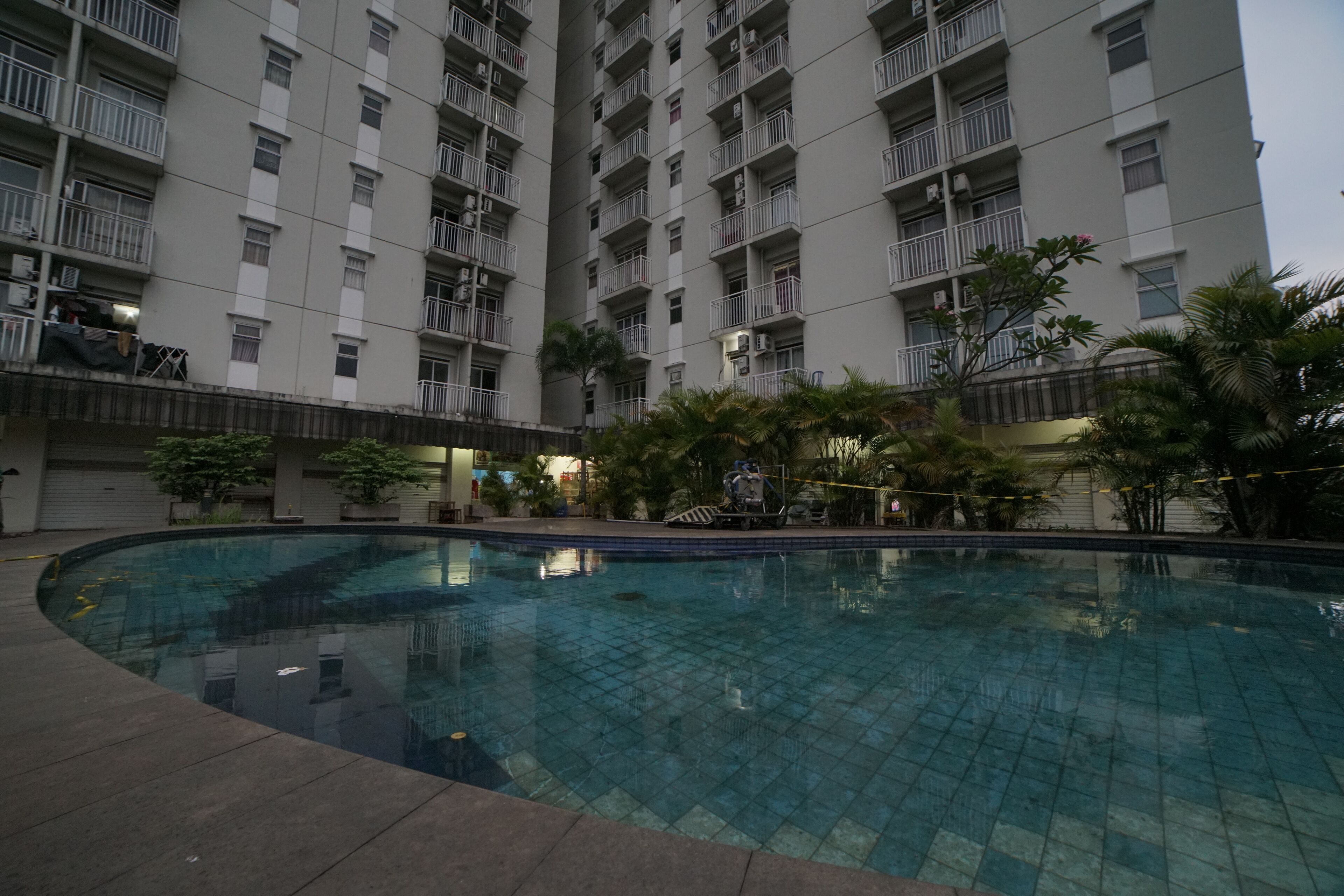 Una piscina rodeada por un edificio de gran altura con balcones y palmeras.