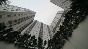 A high-rise building with multiple floors, balconies, and a surrounding area with trees. - Apartment Bogor Valley (Bogor)