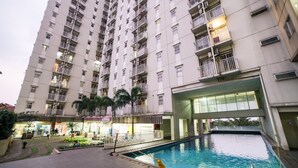 A high-rise residential building with a swimming pool, balconies, and a small garden area. - Apartment Bogor Valley (Bogor)
