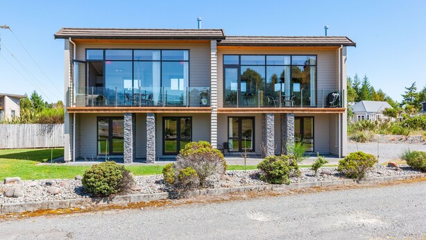 A modern two-story house with large windows, a balcony, and a stone facade. - Parkview Apartments (National Park Village)