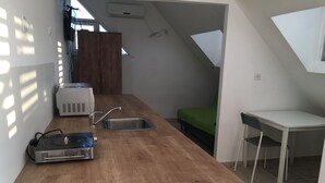 A compact kitchen with a wooden countertop, a sink, a toaster, and a projector.