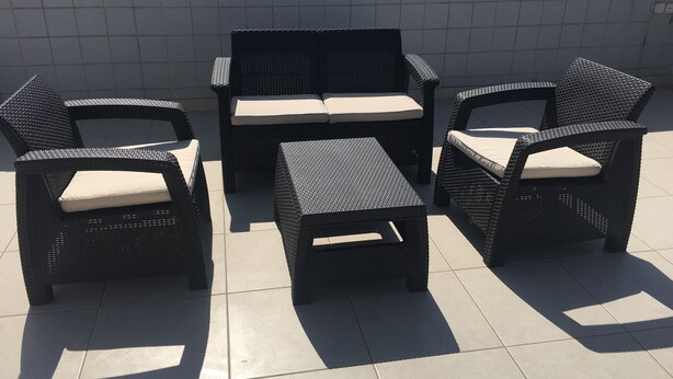 A patio area with wicker furniture including two chairs, a sofa, and a small table.